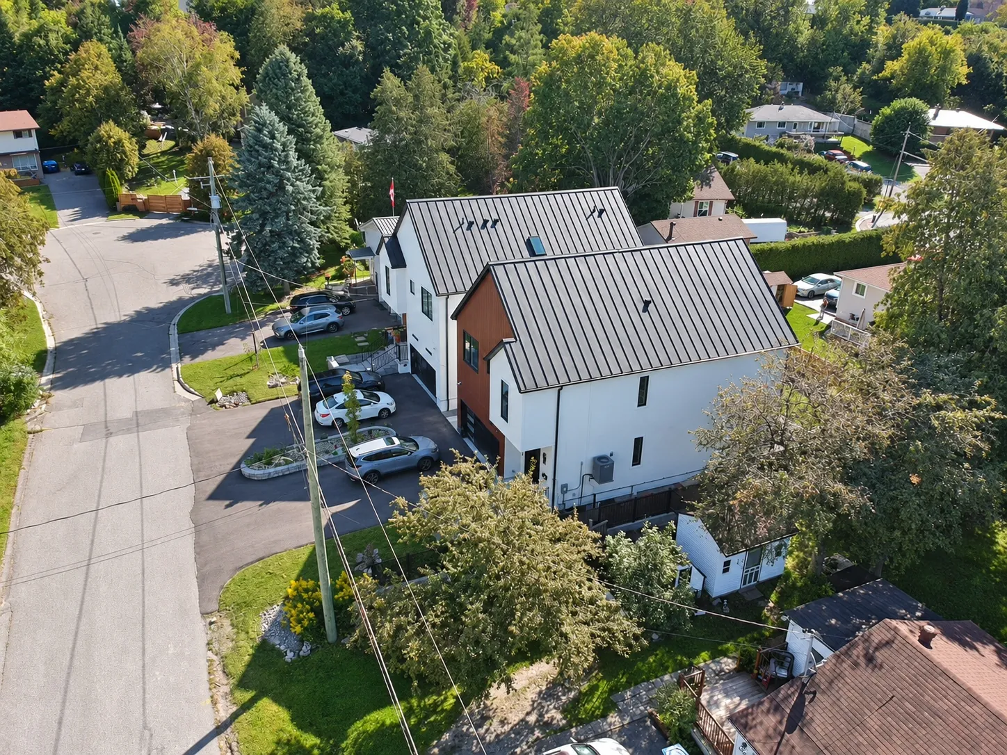 From the air behind the house: the black roof, the deck and the lawn, the street beyond