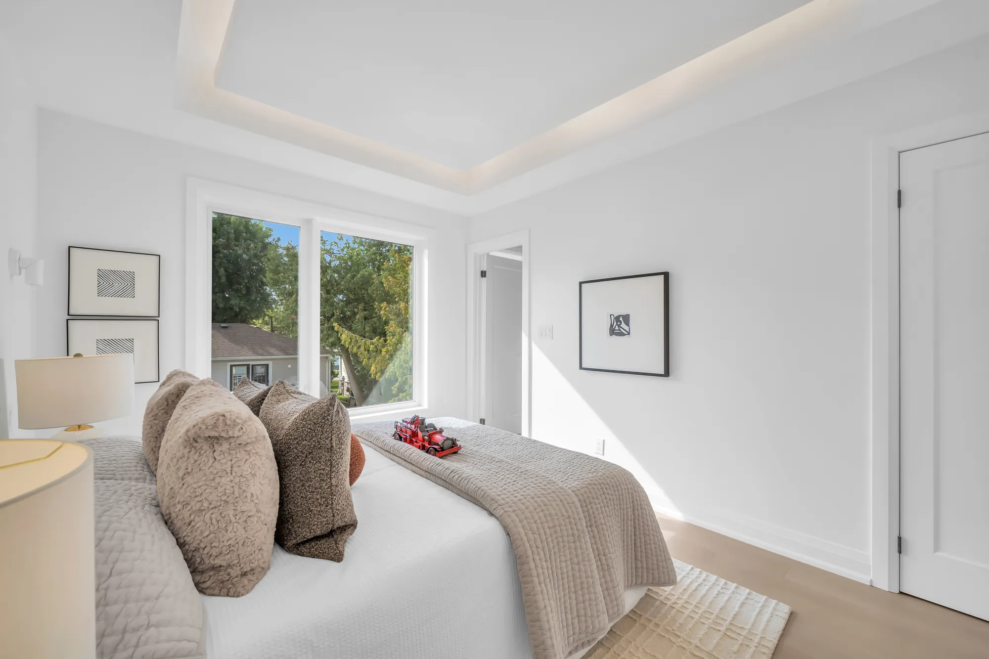 The second bedroom from the door: the bed with its cushions, the window, framed prints