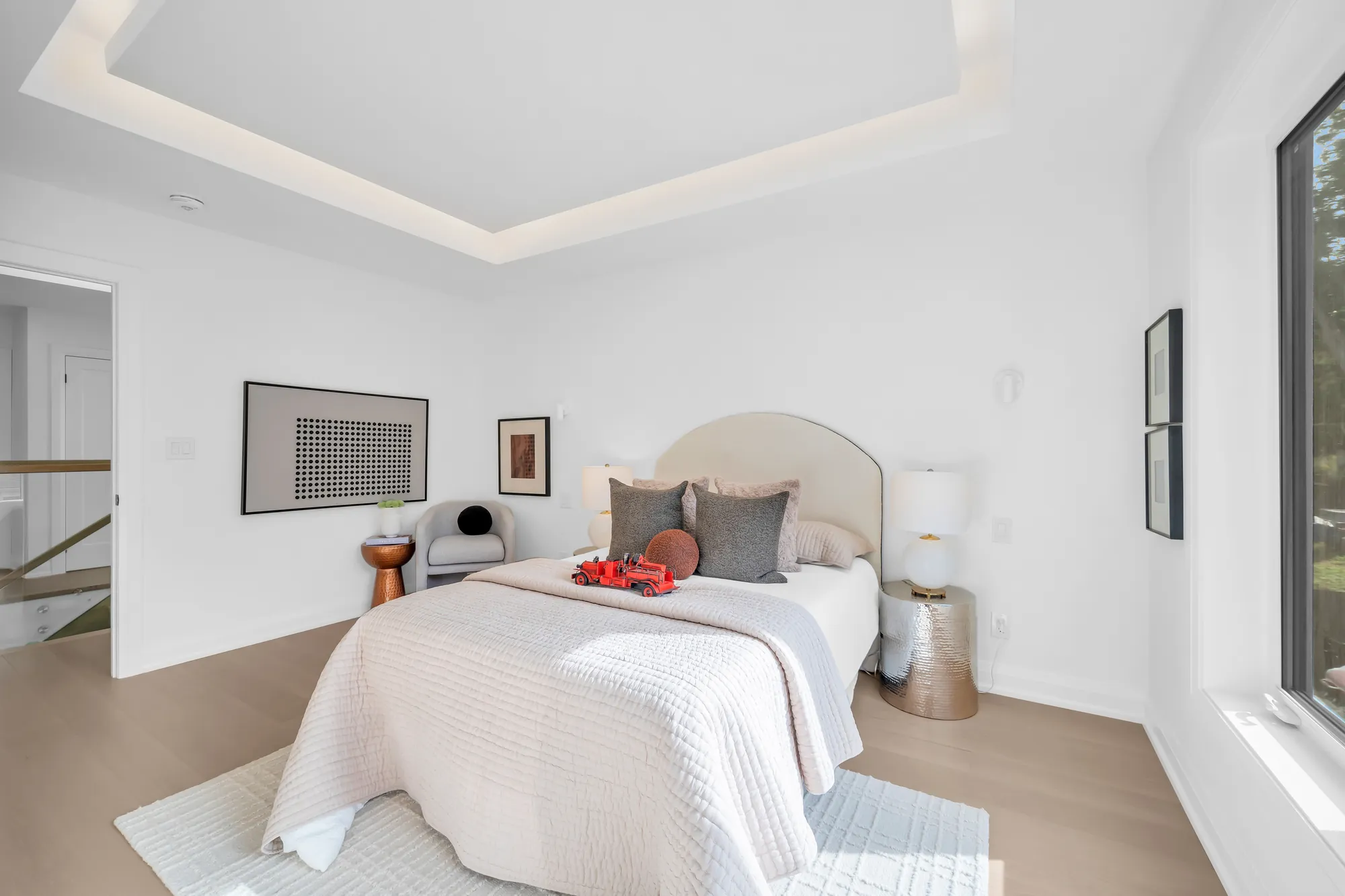 The second bedroom from the window side: the bed, its door to the hall, the tray ceiling