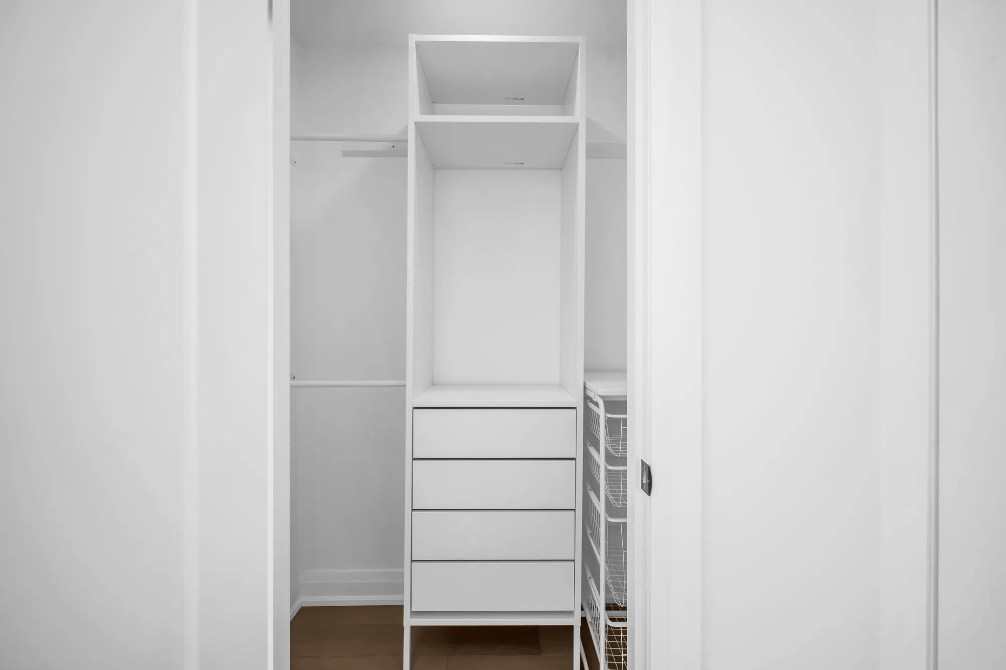 The walk-in closet: white built-in shelves, hanging rails and drawers on three sides