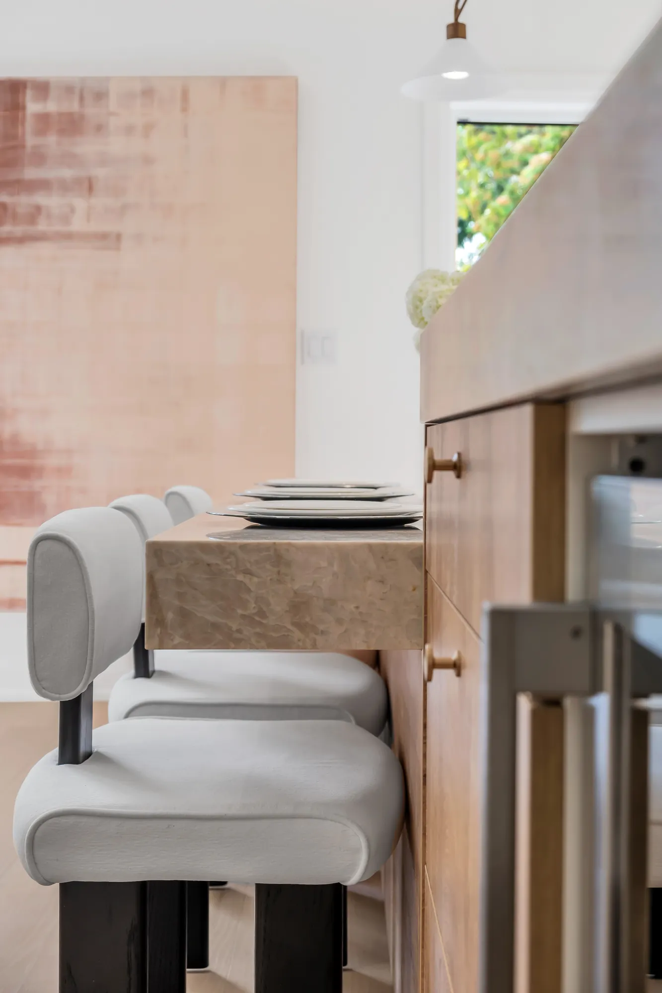 A detail of the island: white leather stools with black legs at the oak base, the stone counter above
