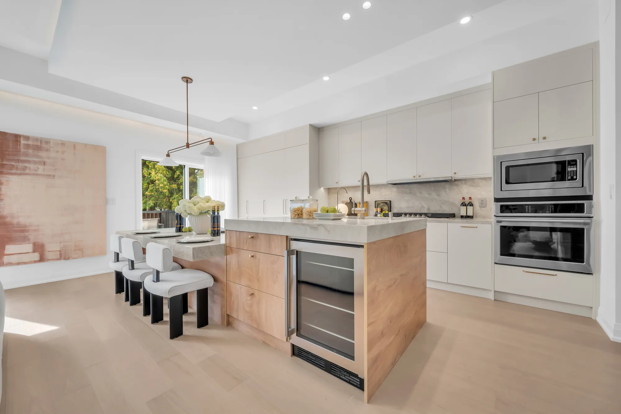 The kitchen's tall cabinets: the wall oven and microwave, the wine cooler under the island's end, the cooktop wall beyond