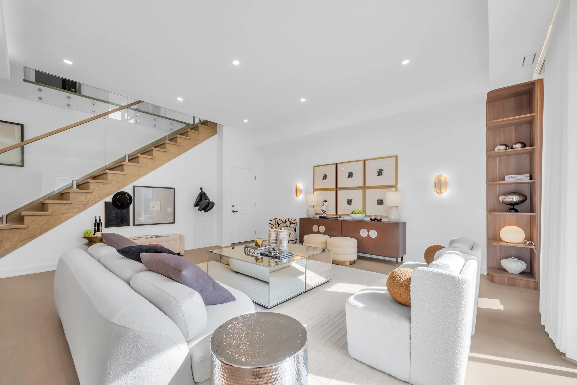 The living room toward the stair: a white sofa, the glass rail, the oak shelf unit, the console