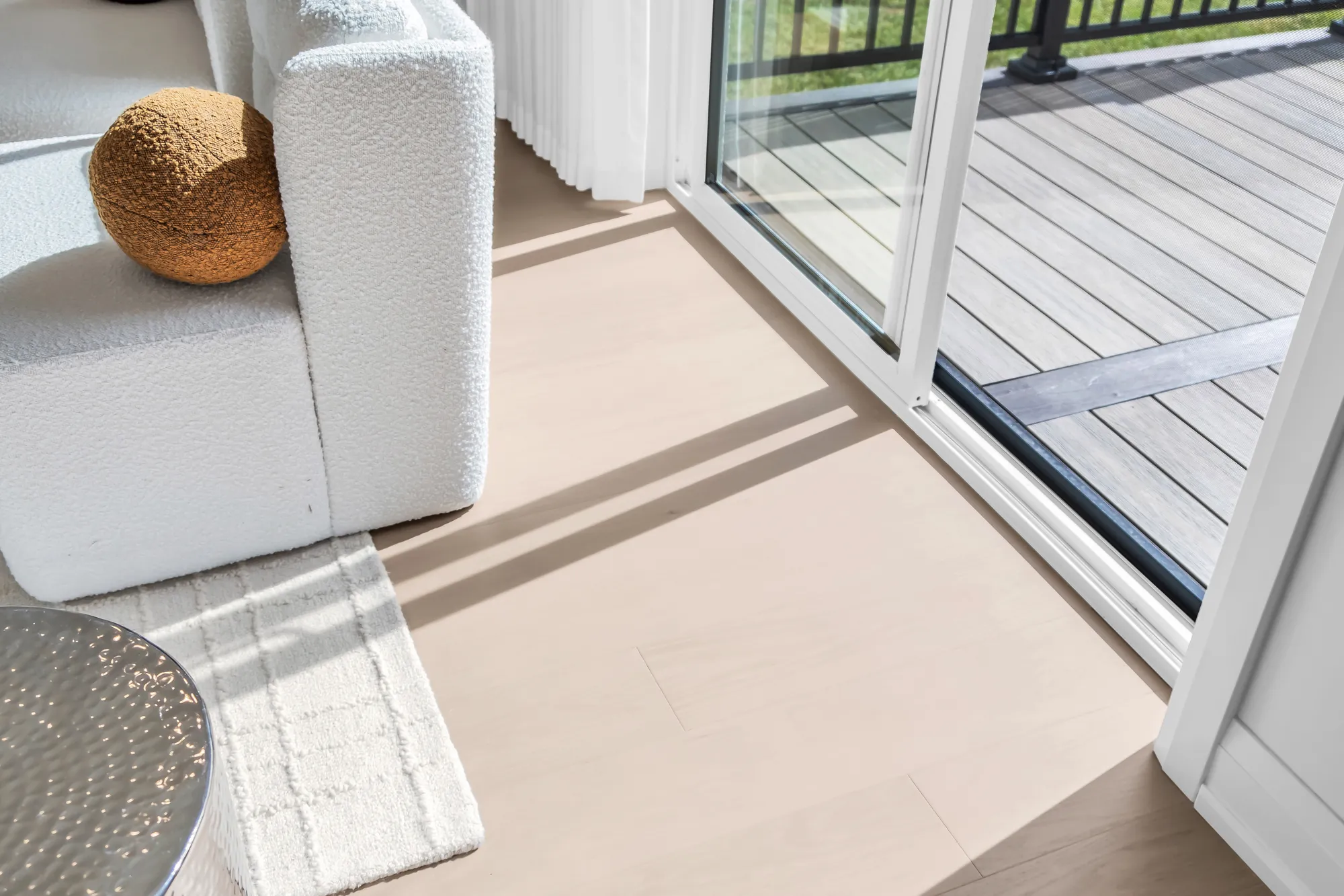 The sliding door open to the deck from beside the sofa: the oak floor, the deck boards, the railing