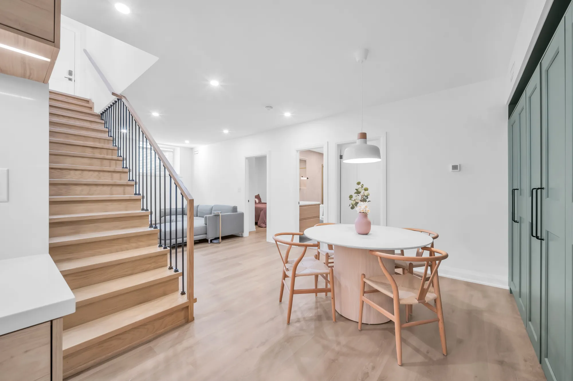 The foot of the lower stair: the dining table and chairs, the hall to the bedrooms, a pendant